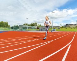 Full length of fit young woman running on sports tracks