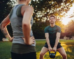 fitness, sport, exercising and lifestyle concept - couple stretching leg on stands of stadium
